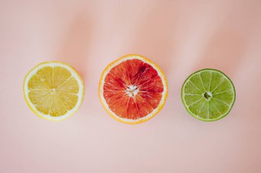 Düz dilimlenmiş limon, kan turuncusu ve pembe arkaplanlı.
