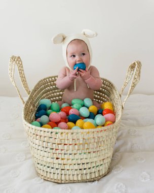 Easter Bunny Baby Sitting in Basket Eating egg clipart