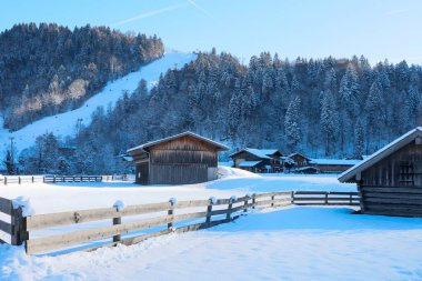 Karlı bir dağın altındaki Alp köyü