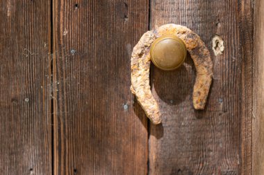 Rusty Old Horseshoe over Gold Knob on Rustic Wood Door Good Luck clipart