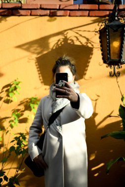 Kadın dışarıda, İspanyol bahçesinde selfie çekiyor.