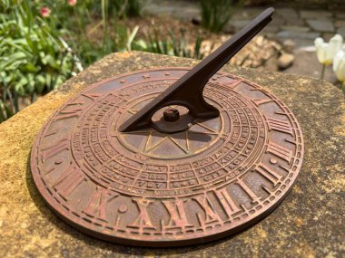 Old Sundial Bronze on Rustic Concrete in Bright Flower Garden clipart