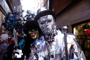 Şenlikli dar bir sokakta renkli kostümlü figürler