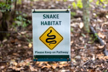 Snake habitat warning sign on a fence in an Australian bush forest clipart