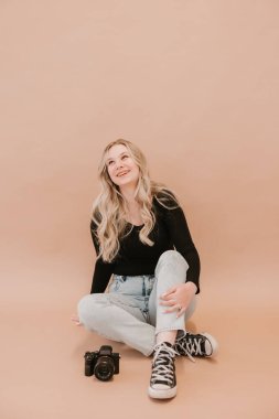 Bej arka planda kameralı genç bayan fotoğrafçı.