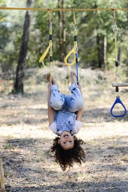 Tulumlu neşeli bir çocuk sarı bir playgro 'da baş aşağı asılı duruyor.