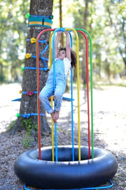 Tulum giymiş bir çocuk renkli oyun alanındaki barlara tutunuyor.