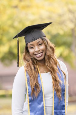 Mezuniyet şapkası ve kuşağı takan bir kadın.