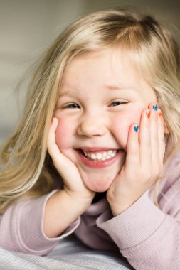 Tırnakları boyalı, gülümseyen neşeli genç bir kızın yakın çekimi.