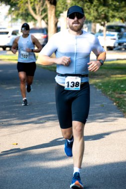 Apple Sprint Triatlonunda ağaçlar üzerinde koşan sporcular