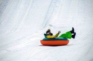 Çocuk karlı dağda tüp kazıyor.