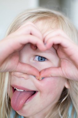 Elleri gözünün üstünde kalp yapan çocuk..