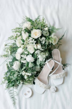 Bridal accessories flatlay of bouquet, pearl heels, and jewelry. clipart