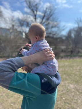Bebek, babamın omuzlarında oturur ilkbaharda parkta yürür