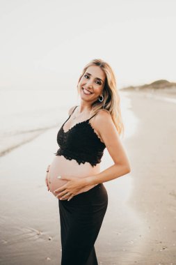 Güzel hamile, siyah giyen bir kadın bekliyor.