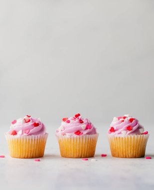 Pembe kaplamalı üç kupa ve beyaz arka planda kalpler..