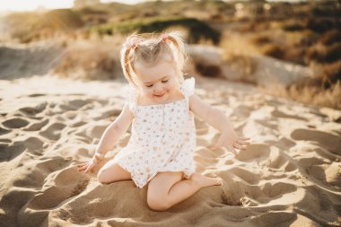 Küçük kız kumsalda oynamaktan mutlu.