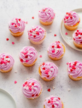 Pembe şekerli küçük paketler ve beyaz arka planda kalpler..