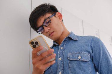 Akıllı telefonuna bakan odaklanmış genç bir adam.