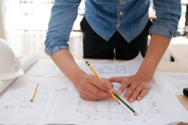Genç mimar çalışma masasında ev planları çiziyor.