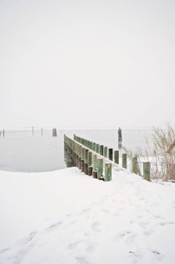 Karla kaplı rıhtım sakin, donmuş bir rıhtıma doğru uzanıyor.
