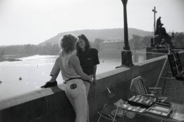 Young lovers sitting on the Charles Bridge in Prague clipart