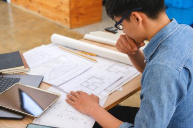 Modern bir çalışma alanının planları üzerinde çalışan bir mimar