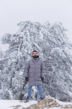 Buz saçağı kaplı çam ağacına ve sütlü gökyüzüne karşı kış yürüyüşçüsü