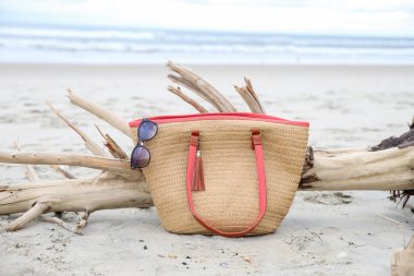 A woven beach bag and sunglasses on the beach of Ocracoke, NC clipart