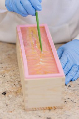 Kadın yemek çubuğuyla el yapımı sabuna narin girdap tasarımları ekliyor..