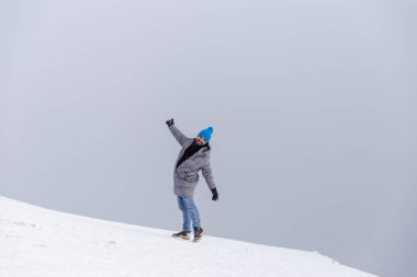 Bulutlu gökyüzüne karşı dağlarda yürüyen komik genç adam.