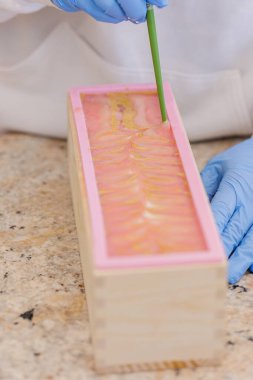 Kadın, yemek çubuğuyla el yapımı sabunla karışık girdaplar yapıyor..