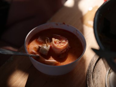 Ahşap masada servis edilen karidesli lezzetli Tom yum çorbası.