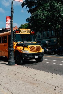 Meşgul bir New York caddesine park etmiş parlak sarı okul otobüsü.