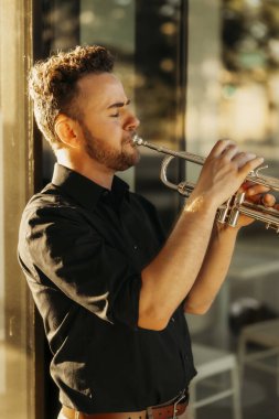 Genç müzisyen altın gün ışığında trompet çalıyor.