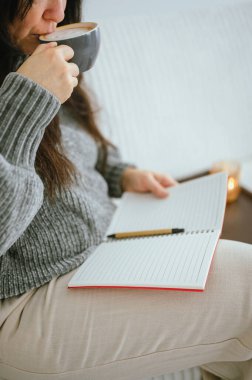 Sabahları günlük tutarken kahvesini yudumlayan bir kadın.