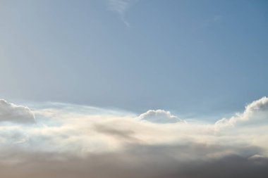 Parlak güneş ışığı mavi gökyüzündeki görkemli bulutları aydınlatıyor.