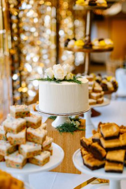 Şenlikli bir etkinlikte tatlı masasında güllerle süslenmiş zarif beyaz pasta.