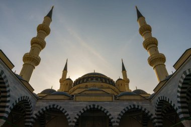 Arkasında mavi gökyüzü olan büyük, sarı ve siyah bir bina.