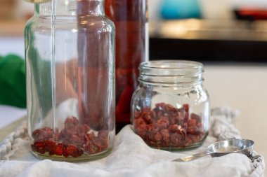 Ayçiçeği yağı, kurumuş gül kalçalarındaki cam kavanoza dökülüyor.