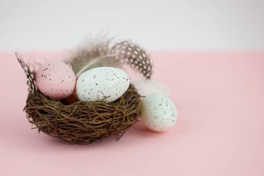 Paskalya yumurtaları pembe arka planda söğüt ağacıyla sepette