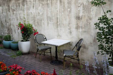 Kapalı bir masa, sıva duvarına karşı saksı bitkileri.