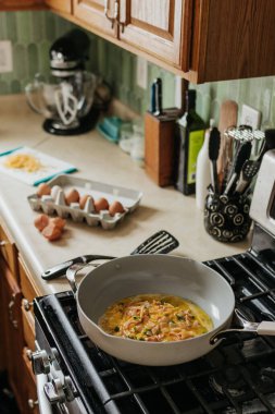 Yumurta, peynir, jambon ve soğan karışımı mutfakta sıcak tavada aşçı.