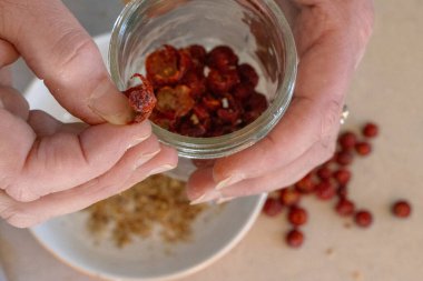 Kurumuş gül kabuğunun ayrıntıları kasede tohumlarla birlikte elle tutuluyor..