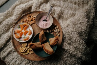 Sıcak kahvaltı tepsisi yoğurt, ekmek ve yumuşak bir battaniyede meyve.