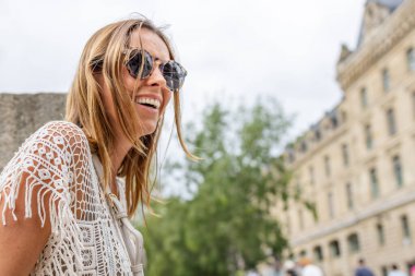 Kadın gülüyor ve güneş gözlüğü takıyor.