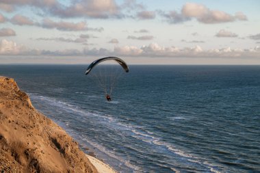 Danimarka 'nın engebeli kıyı kayalıkları yakınlarında Kuzey Denizi üzerinde süzülen paraglider