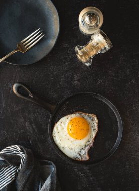 Tavada kızarmış yumurta ve siyah arka planda plaka..