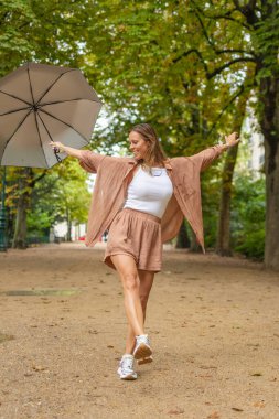 Paris parkında kollarını açmış dans eden bir kadın.