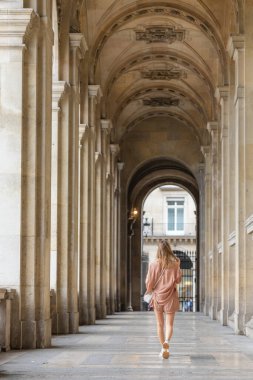 Paris 'te mimari bir koridorda yürüyen bir kadın.